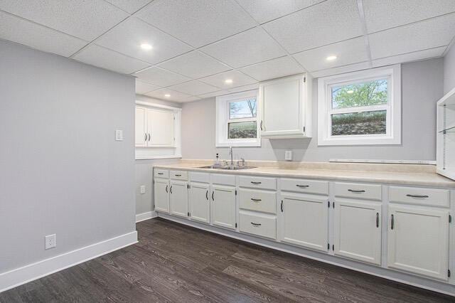 2737 Patricia Dr, Muskegon, MI 49445 - kitchen featuring dark wood-style flooring, white cabinetry, light countertops, a drop ceiling, and plenty of natural light