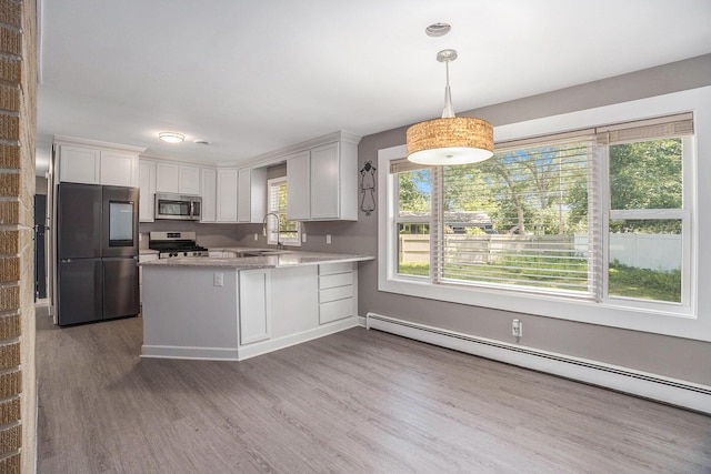 2737 Patricia Dr, Muskegon, MI 49445 - kitchen with stainless steel appliances, a baseboard radiator, a peninsula, wood finished floors, and white cabinetry