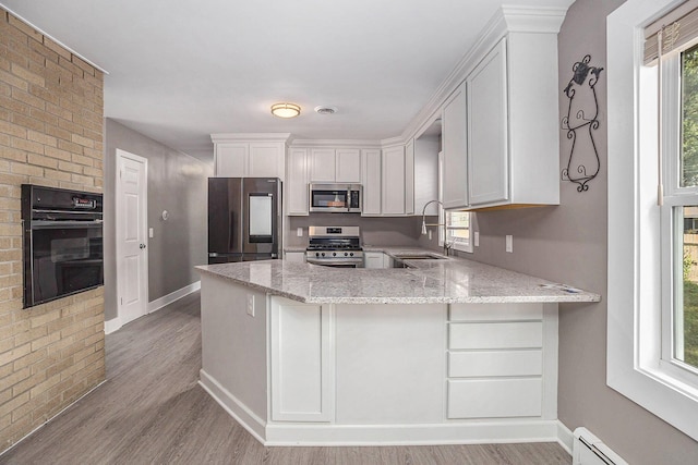 2737 Patricia Dr, Muskegon, MI 49445 - kitchen featuring stainless steel appliances, baseboard heating, light stone countertops, light wood-type flooring, and a peninsula