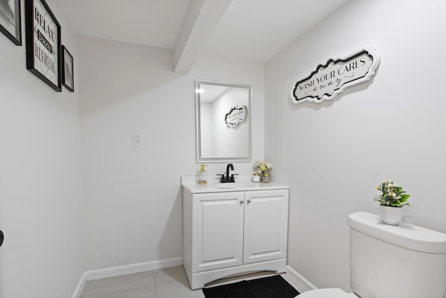 bathroom with toilet, vanity, tile patterned flooring, and baseboards