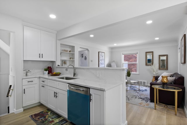 kitchen with dishwasher, a sink, a peninsula, light wood-type flooring, and open floor plan