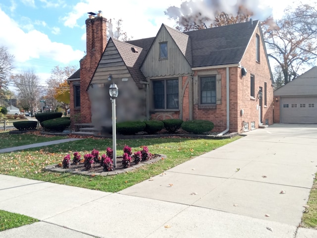23211 Myrtle St, Dearborn, MI 48128 - tudor-style house featuring a shingled roof, brick siding, an outdoor structure, and a chimney