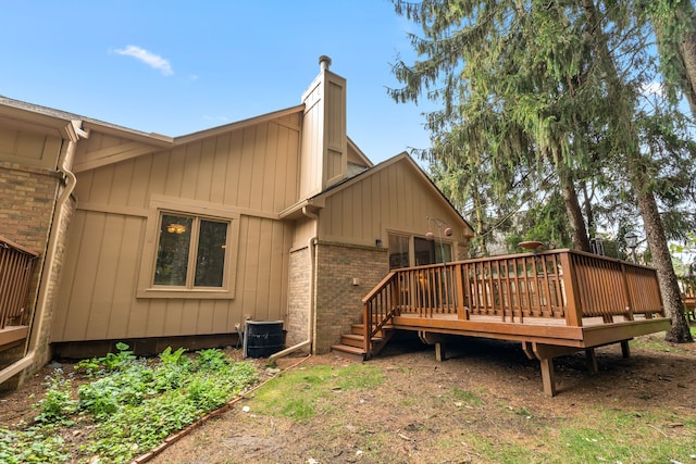 rear view of property with central air condition unit, brick siding, a chimney, and a deck