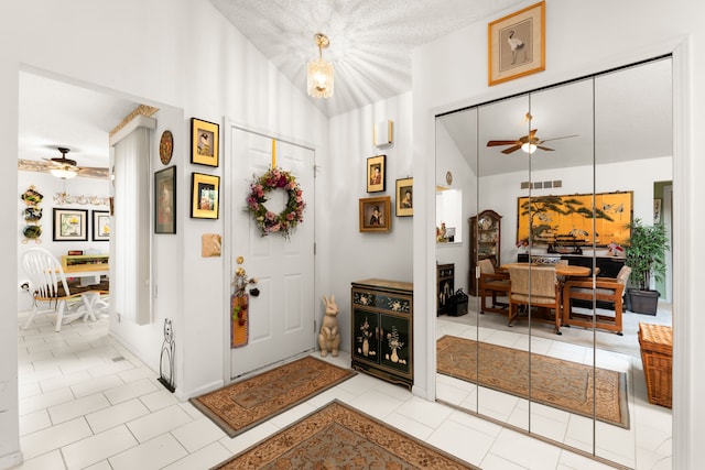entrance foyer featuring visible vents, ceiling fan, light tile patterned flooring, and high vaulted ceiling