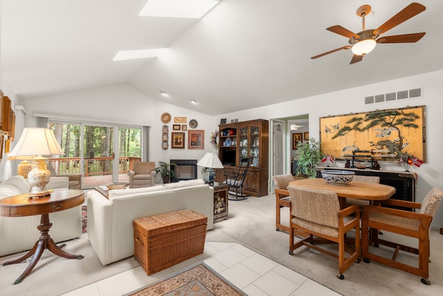 living room with light colored carpet, a ceiling fan, visible vents, and lofted ceiling with skylight