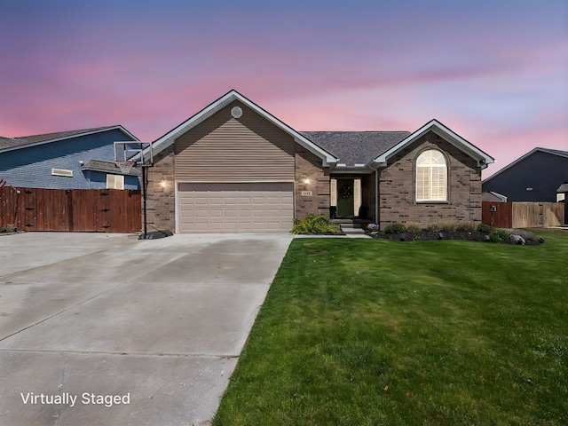 ranch-style home with a yard, driveway, brick siding, fence, and a garage