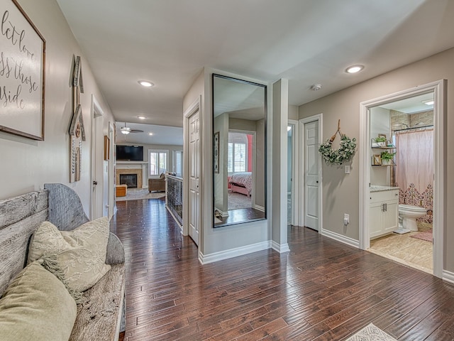 hall featuring wood finished floors, baseboards, and recessed lighting