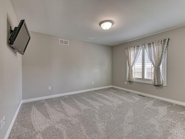 carpeted empty room featuring baseboards and visible vents