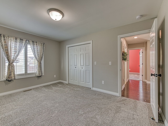 unfurnished bedroom with dark colored carpet, a closet, baseboards, and visible vents