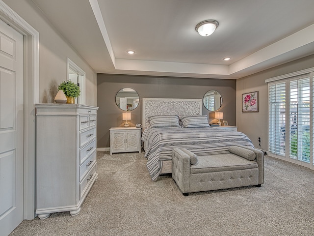 bedroom with light carpet, baseboards, a raised ceiling, and recessed lighting