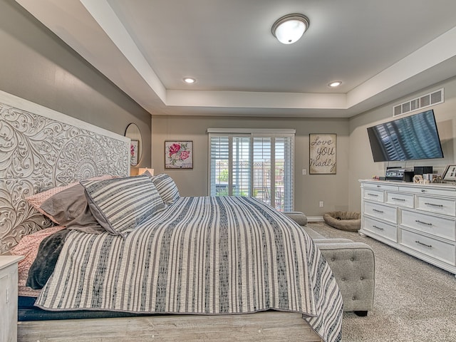 carpeted bedroom featuring a raised ceiling, baseboards, visible vents, and access to exterior