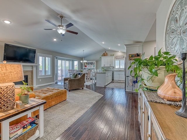 living area with a healthy amount of sunlight, a high end fireplace, ceiling fan with notable chandelier, and vaulted ceiling