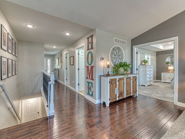 corridor with recessed lighting, baseboards, visible vents, wood finished floors, and an upstairs landing