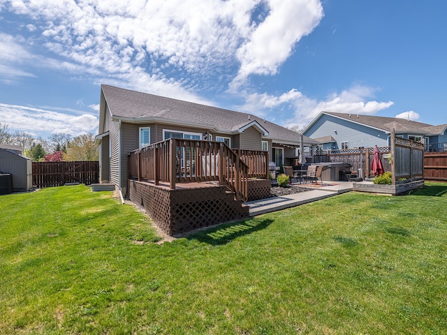 back of property with a lawn, a deck, and a fenced backyard