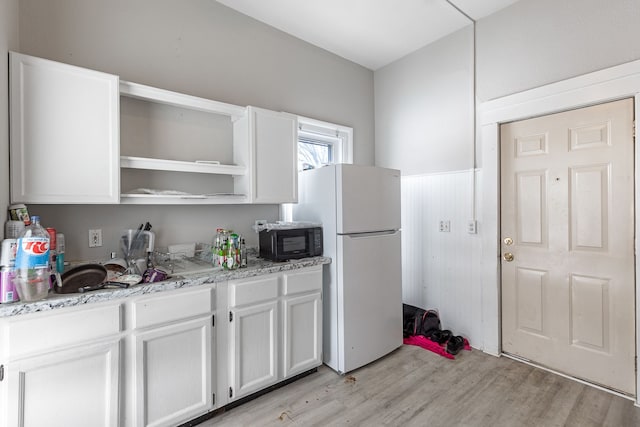 124 S Ottawa St, Tecumseh, MI 49286 - kitchen with freestanding refrigerator, black microwave, open shelves, white cabinets, and light wood-type flooring