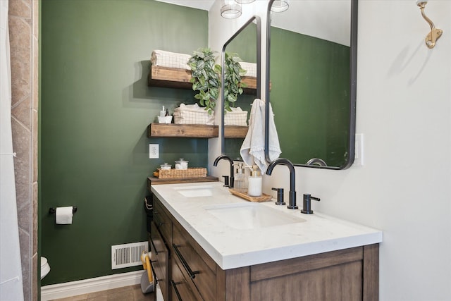 bathroom featuring a sink, double vanity, baseboards, and visible vents
