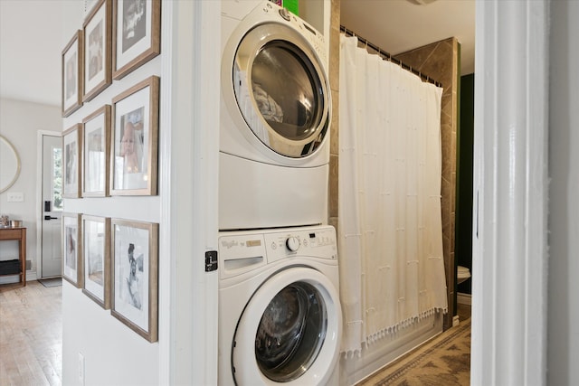 washroom featuring laundry area, stacked washer / dryer, and light wood-style flooring