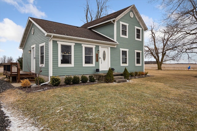 traditional-style house with a front lawn, a shingled roof, and a wooden deck