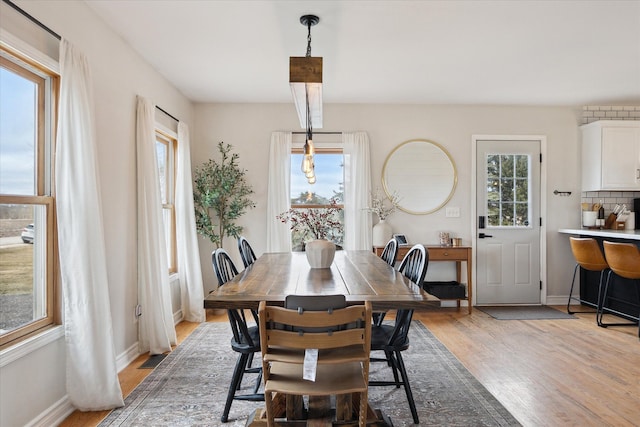 dining space featuring light wood-style floors and baseboards