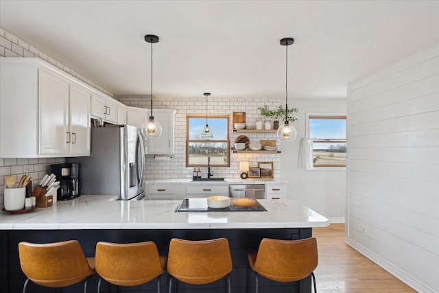 kitchen with backsplash, stainless steel appliances, a peninsula, and white cabinets