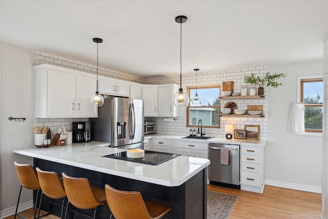 kitchen with a sink, a peninsula, decorative backsplash, and appliances with stainless steel finishes