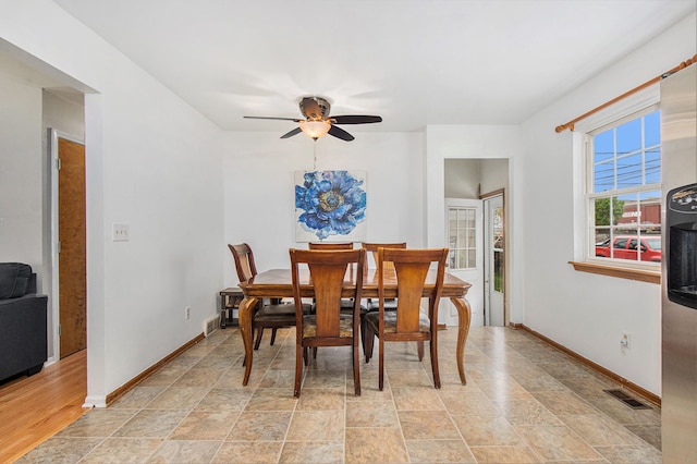 dining area with baseboards, stone finish floor, visible vents, and a ceiling fan