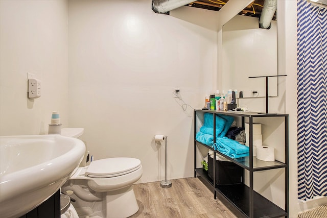 full bath with toilet, wood finished floors, and a sink