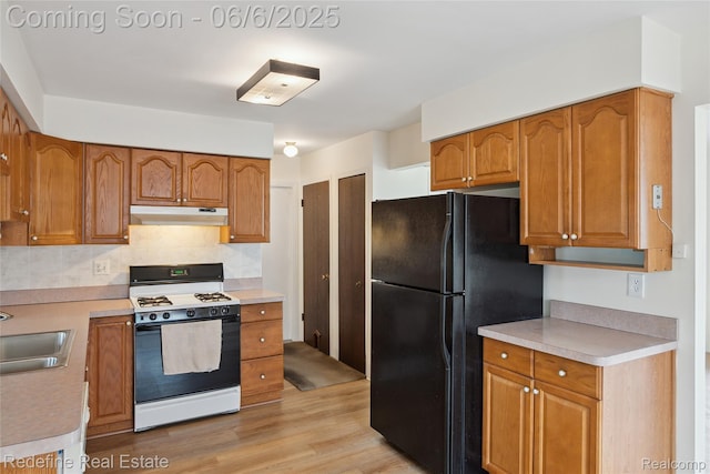 42127 Addison Ave, Canton, MI 48187 - kitchen with range with gas stovetop, under cabinet range hood, freestanding refrigerator, a sink, and light wood finished floors