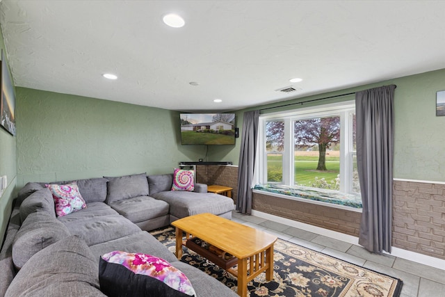 living area with light tile patterned flooring, a textured wall, visible vents, and recessed lighting