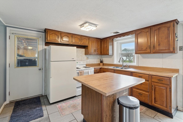 kitchen with a sink, white appliances, wood counters, a textured ceiling, and visible vents