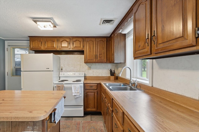 kitchen featuring brown cabinets, a sink, white appliances, visible vents, and butcher block countertops