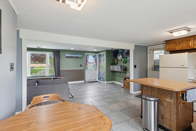 kitchen with freestanding refrigerator, open floor plan, a textured ceiling, baseboards, and butcher block countertops