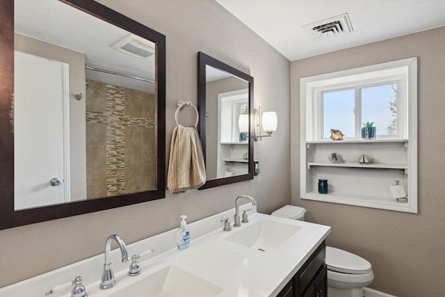 bathroom with toilet, visible vents, a sink, and double vanity