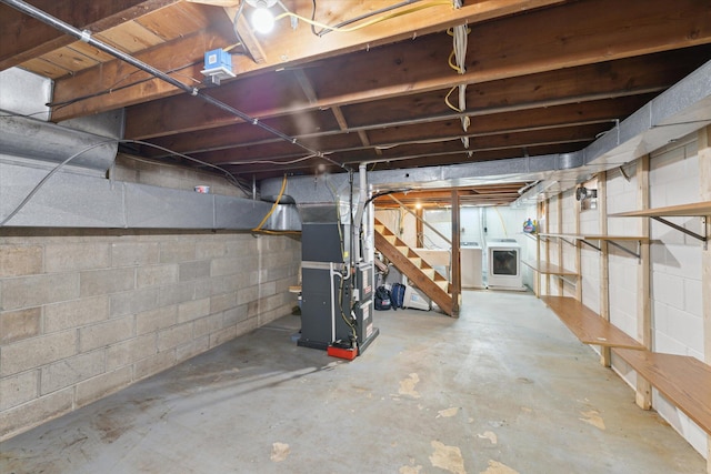 unfinished basement featuring heating unit, stairway, and washer / clothes dryer
