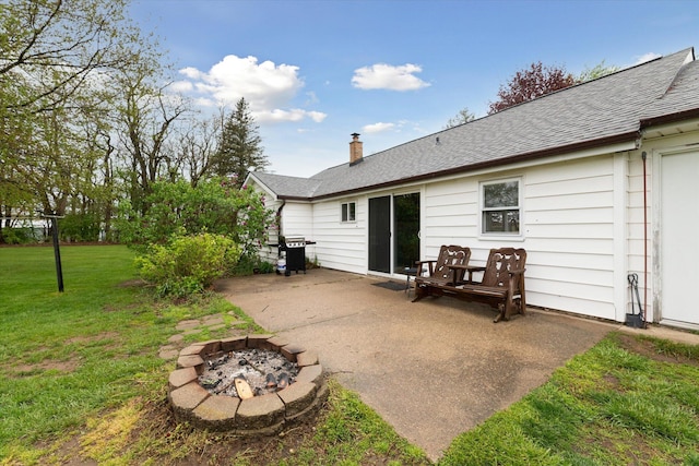 back of house featuring a yard, a chimney, a patio, an outdoor fire pit, and a shingled roof