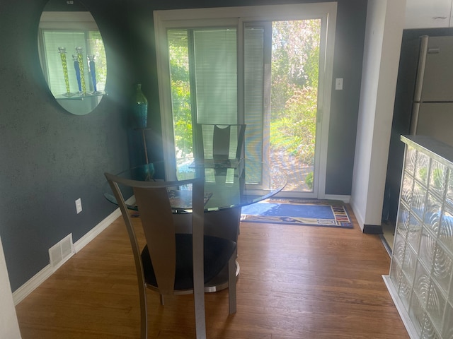 dining space with baseboards, visible vents, and wood finished floors