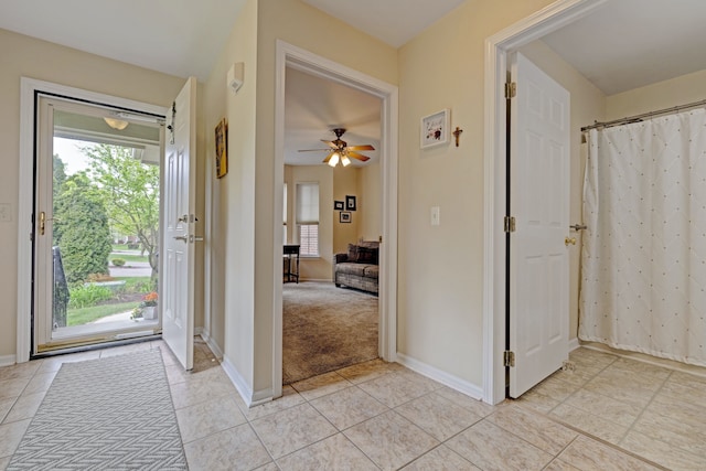 entryway with ceiling fan, light carpet, baseboards, and light tile patterned floors