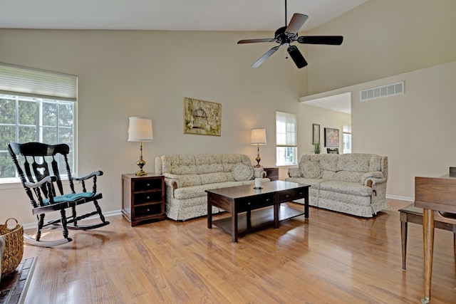 living area featuring lofted ceiling, wood finished floors, visible vents, a ceiling fan, and baseboards