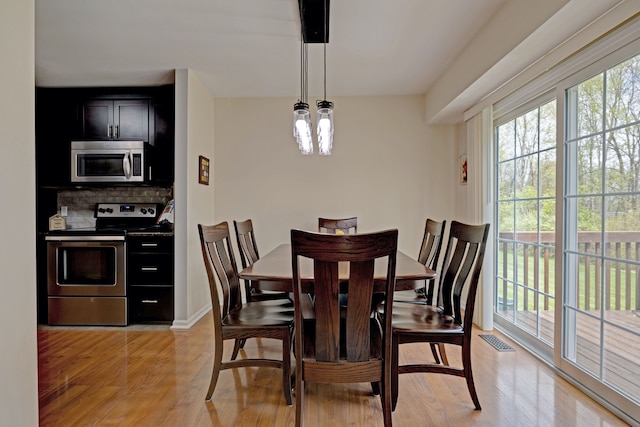 dining space with baseboards, light wood-type flooring, and visible vents