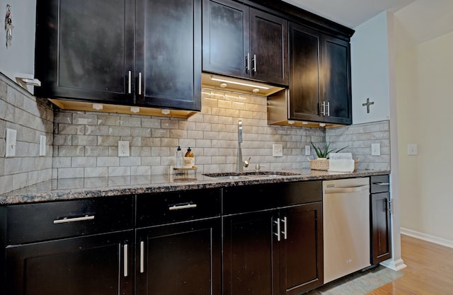 kitchen with a sink, tasteful backsplash, dishwasher, light stone countertops, and light wood-style floors