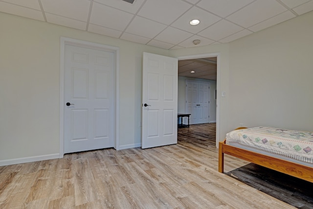 bedroom with light wood-type flooring, a drop ceiling, baseboards, and recessed lighting