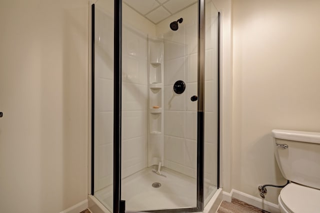 full bath with toilet, baseboards, and a stall shower
