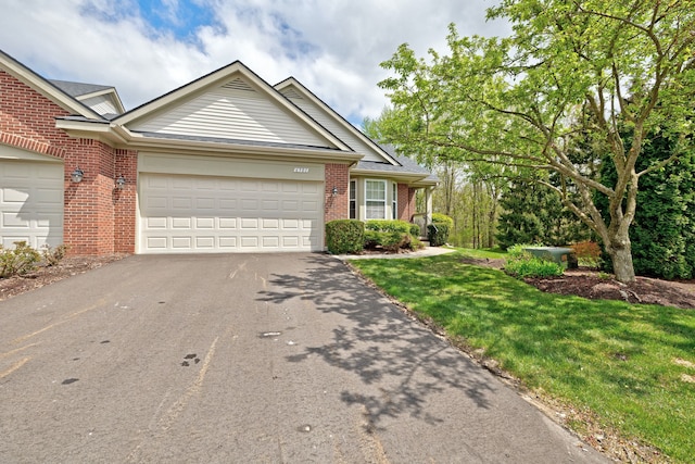 view of front of home featuring aphalt driveway, a garage, a front lawn, and brick siding