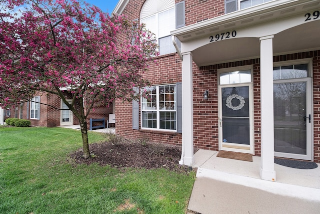 property entrance featuring brick siding and a lawn