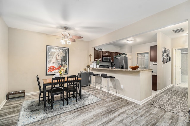 dining area featuring baseboards, ceiling fan, light wood-style flooring, and visible vents