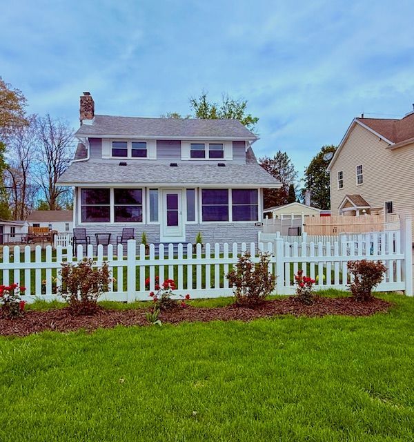11952 N Main St, Whitmore Lake, MI 48189 - view of front of home with a front lawn, a fenced front yard, a chimney, and stone siding