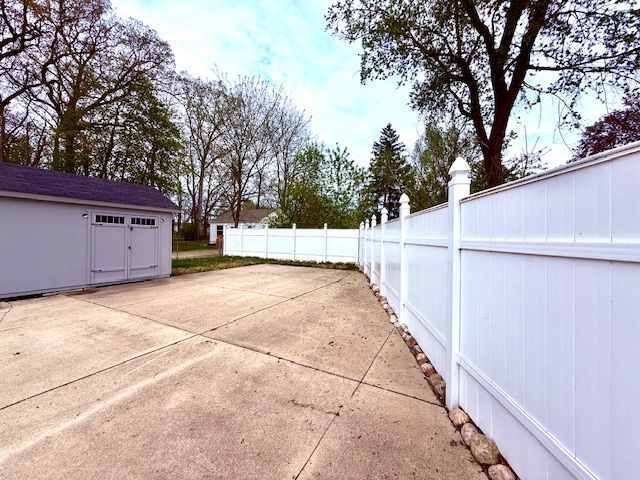view of patio featuring a storage unit, fence, and an outbuilding