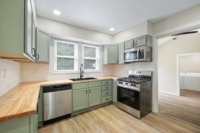 kitchen featuring green cabinets, butcher block counters, appliances with stainless steel finishes, and a sink