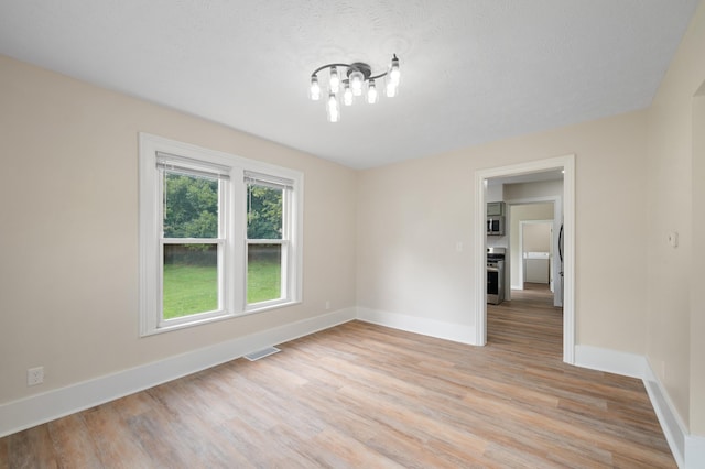 spare room featuring light wood finished floors, baseboards, and visible vents
