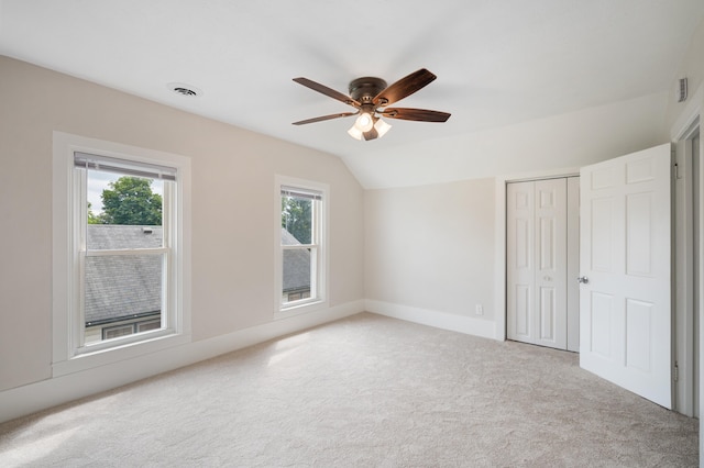 unfurnished bedroom featuring carpet flooring, multiple windows, a closet, and lofted ceiling